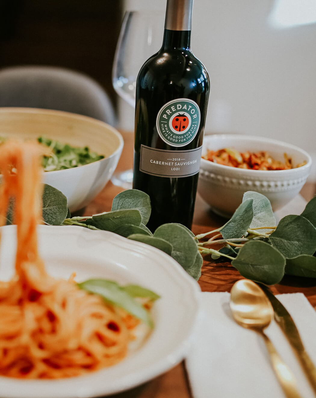 predator wine on table with spaghetti next to it